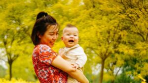 A smiling mother holds her giggling toddler