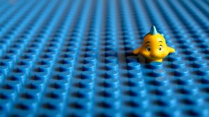 A single fish sits anchored on a board with lego-style fitting